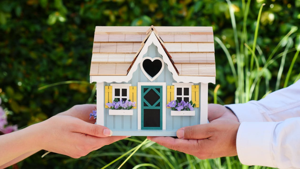 People holding a miniature wooden house