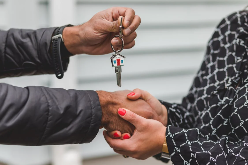 Two people shaking hands with a house key