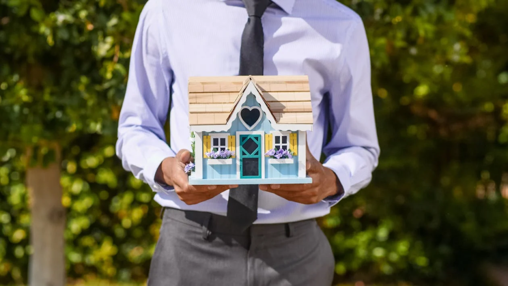 A real estate agent holding a miniature house 