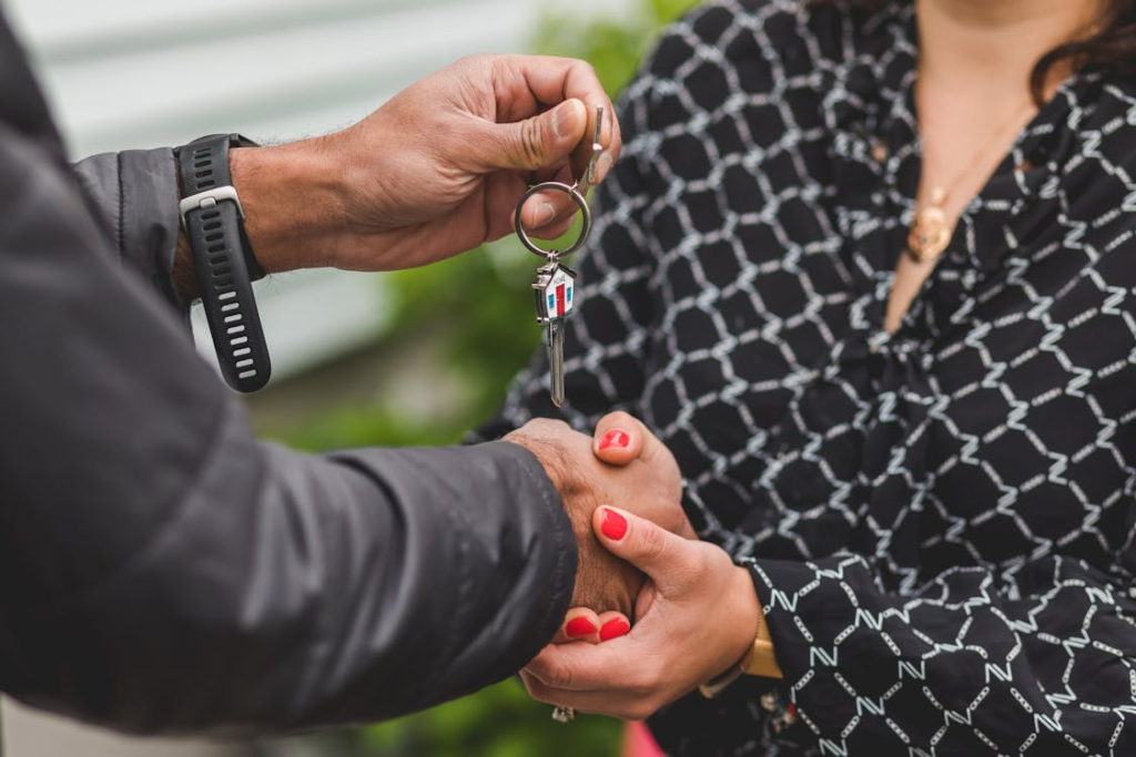 A person holding a key and shaking a woman’s hand