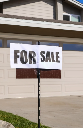 This image shows for sale sign in front of a house.