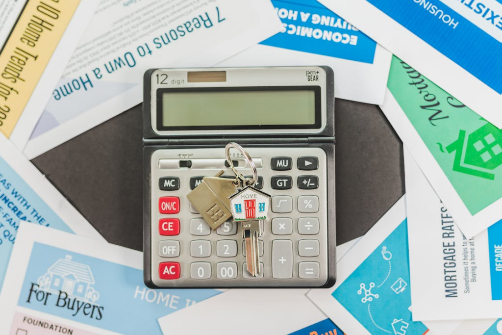 a realtor's documents placed around a calculator with house keys on it