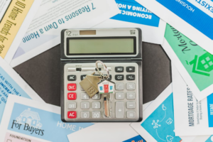 a realtor's documents placed around a calculator with house keys on it