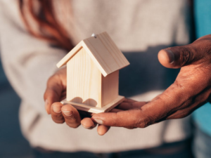 a couple holding a miniature house