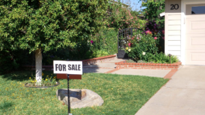 a for sale sign on the front lawn of a property
